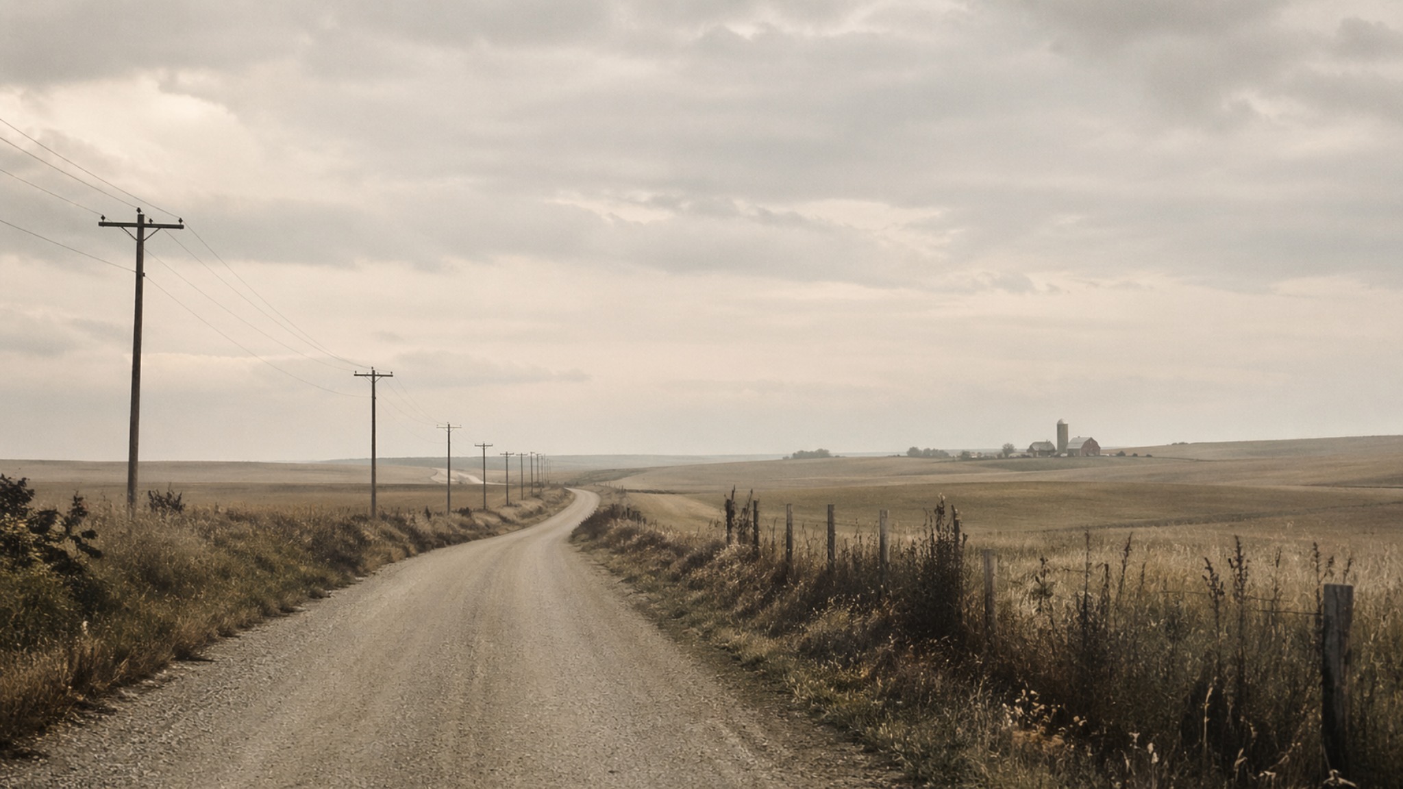 Open rural road leading toward a distant farm